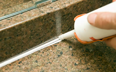 Kitchen maintenance - applying silicone to a granite sink backsplash